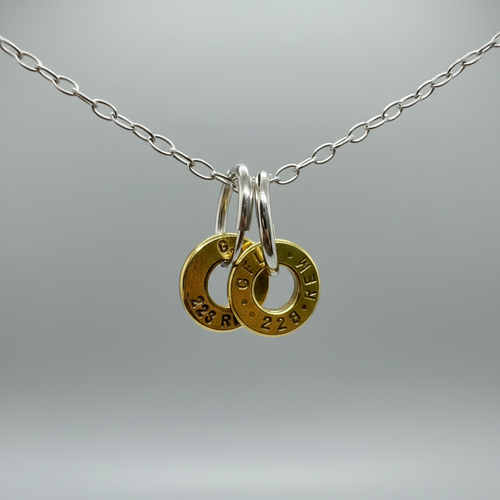 Huntress Hoops - pair of handcrafted hoops from different brass bullet casings mounted on silver bands with chain, studio photography against dark and light background